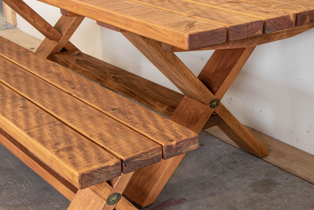 X-Leg outdoor table in Honey macrocarpa, side view