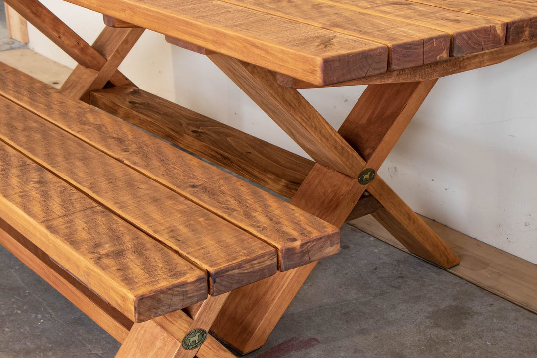 X-Leg outdoor table in Honey macrocarpa, side view